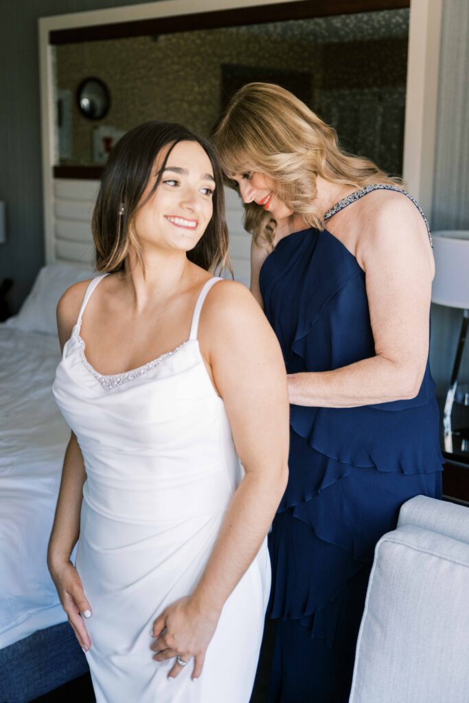 bride getting into wedding dress with mom